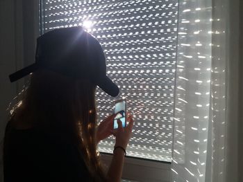 Rear view of woman photographing illuminated smart phone