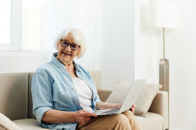 Young woman using digital tablet while sitting at home