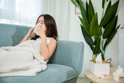 Young woman sitting on sofa at home