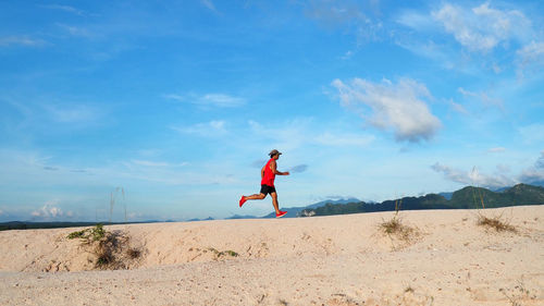 Full length of woman walking on beach against sky