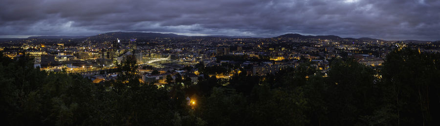 High angle view of illuminated city against sky at dusk