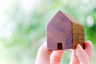 Cropped hand of person holding model home outdoors