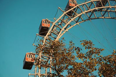 Low angle view of ferris wheel against clear blue sky