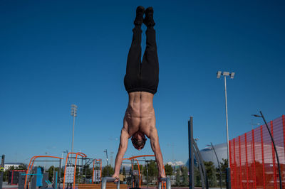 Low angle view of man standing against clear blue sky