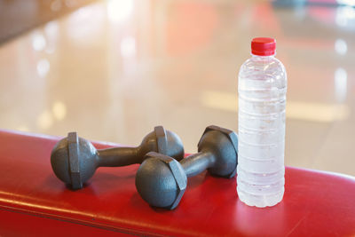 Close-up of bottle with dumbbells on table