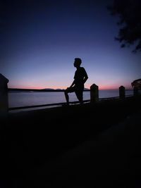 Silhouette man standing on beach against sky during sunset