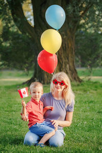 Full length of girl holding balloons on field