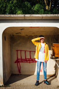 Portrait of boy shielding eyes while standing against wall