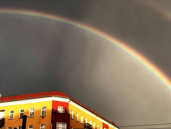 Low angle view of rainbow over building against sky