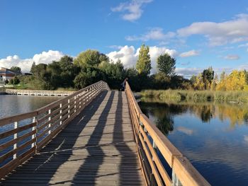 Footbridge over lake against sky