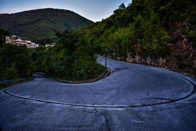 Road amidst trees in city against sky