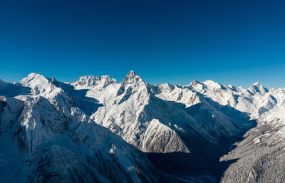 Scenic view of snowcapped mountains against clear blue sky