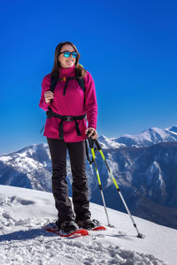 Low angle view of man skiing on snowcapped mountain against clear blue sky