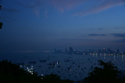 High angle view of city by sea against sky at dusk