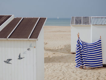 Lounge chairs on beach against clear sky