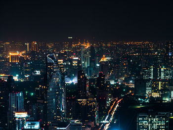 High angle view of illuminated city buildings against sky at night