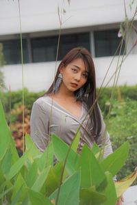 Portrait of young woman standing against plants