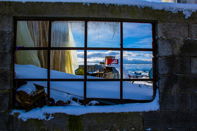 Abandoned building covered with snow seen through window