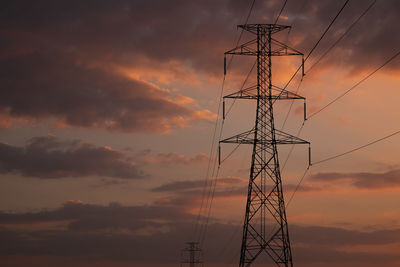 Low angle view of silhouette electricity pylon against sky during sunset