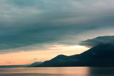 Scenic view of sea and mountains against dramatic sky