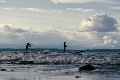 People surfing in sea against sky