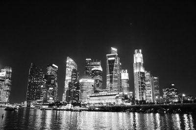 Illuminated city skyline by river at night