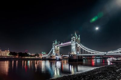 Illuminated suspension bridge over river at night