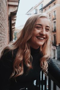 Portrait of smiling young woman standing against built structure