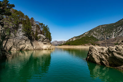 Scenic view of lake and mountains against blue sky