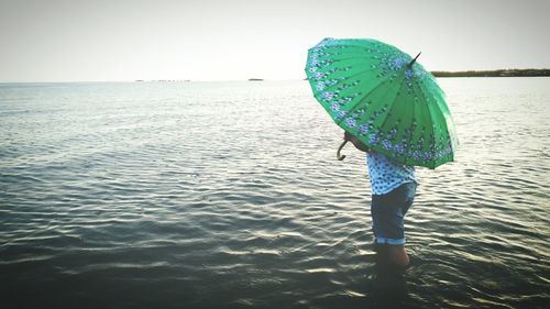Low section of woman standing on beach against clear sky