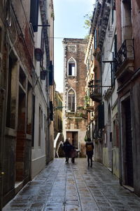 People walking on footpath amidst buildings in city