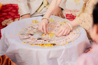 Midsection of couple with paper currency at table during wedding ceremony