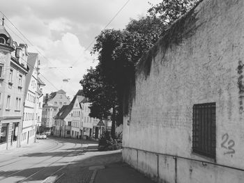 Street amidst trees against sky in city