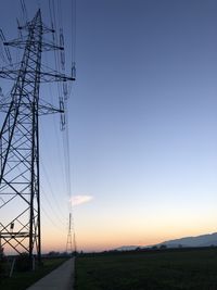 Low angle view of electricity pylon on field against clear sky