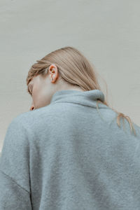 Rear view of woman with blond hair against wall