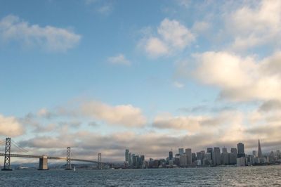 Bay bridge over lake by city against sky