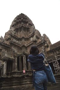 Rear view of senior woman against temple against clear sky