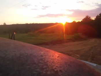 Road by landscape against sky during sunset