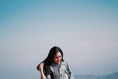 Portrait of a smiling young woman standing against sky