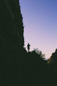 Low angle view of silhouette man standing on rock against sky