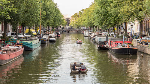 Boats moored in an amsterdam canal lined with trees