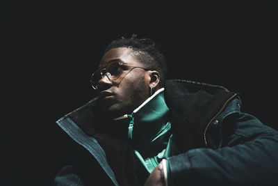 Portrait of young man against black background