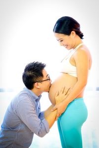 Side view of man kissing stomach of pregnant woman