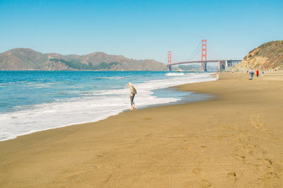 Woman walking at beach against clear sky