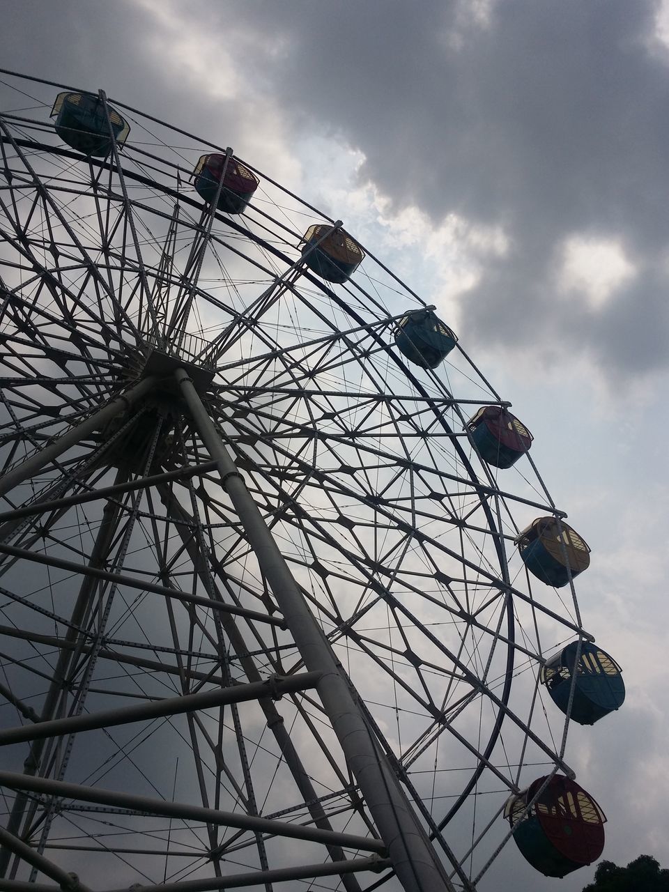 low angle view, amusement park, amusement park ride, ferris wheel, sky, arts culture and entertainment, cloud - sky, cloud, fun, built structure, cloudy, silhouette, metal, enjoyment, outdoors, day, no people, fairground ride, architecture, dusk