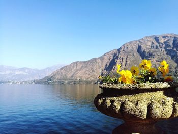 Scenic view of lake by mountains against clear blue sky