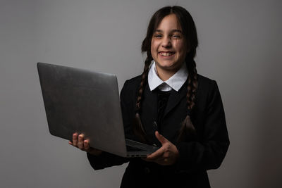 A girl with braids in a gothic style on a dark background with laptop