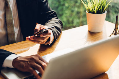 Midsection of businessman using laptop at table