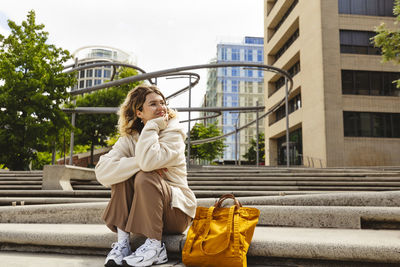 Smiling young woman sitting on staircase at hafencity