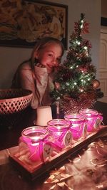 Girl in illuminated christmas tree at home